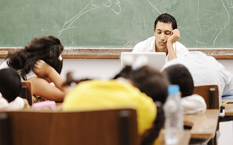 معلمی که در کلاس نشسته و با حالت چهره‌ی ناراحت یا مضطرب، احساس ناکافی بودن و فشار روانی را تجربه می‌کند.