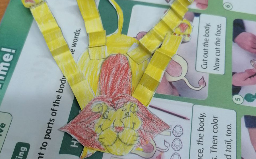 معلم زبان کودک در کلاس زبان کودکان در حال آموزش کاردستی شیر کاغذی، مدیریت رفتارهای چالش‌برانگیز دانش‌آموزان و ایجاد ارتباط انسانی در کلاس