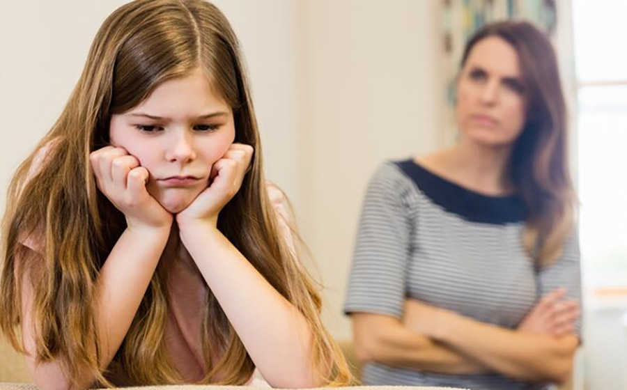 کودک بی‌اعتماد در کلاس زبان با دست‌های زیر چانه و معلم اخمو در پس‌زمینه، تمرکز بر جلب اعتماد و ایجاد محیط امن آموزشی.